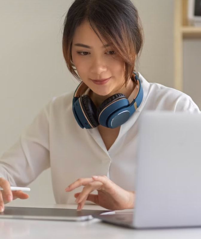 A student with headphones studying on her laptop