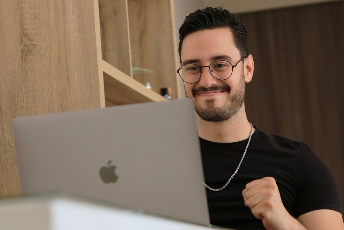 A sales rep smiling during a practice call on his laptop